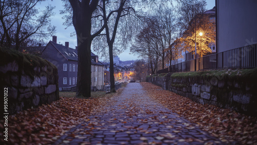 Autumn leaves scattered on a cobblestone path by the riverside at dusk