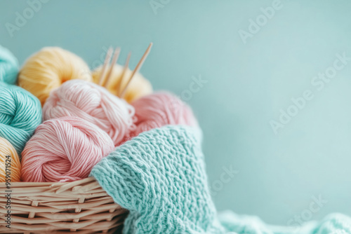 Basket with skeins of merino wool yarn pastel colors, bamboo needls and knit wool sweater, background with copy space on the right.  photo