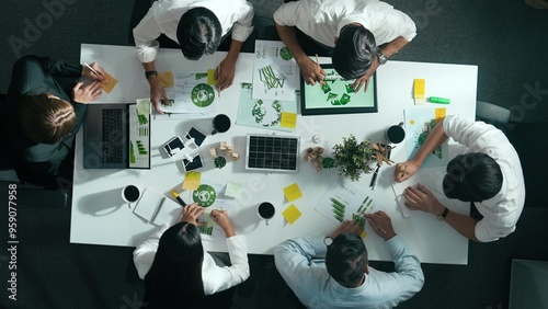 Top down view of business team discussing about using clean energy and sustainable investment at meeting table with wind mill, document with environmental graph and wooden house model. Alimentation.