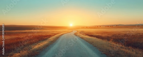 A serene road winding through a golden field, illuminated by a stunning sunrise, creating a peaceful and inspiring landscape.