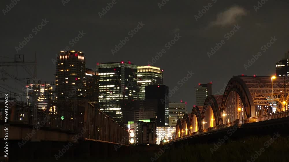 OSAKA, JAPAN - JUNE 2024 : View of train passing at Juso Ohashi bridge and buildings around Osaka station. Time lapse shot at night. OSAKA, JAPAN - JUNE 2024 : View of train passing at Juso Ohashi bridge and buildings around Osaka station. Time lapse shot at night.