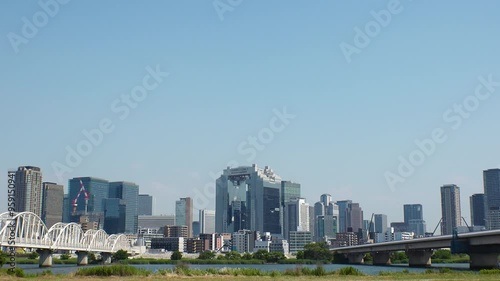 OSAKA, JAPAN - JUNE 2024 : View of buildings around Osaka station, bridge and Yodogawa river. Time lapse shot in sunny daytime. photo