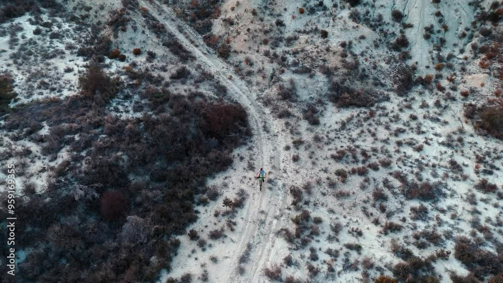 Aerial Flight. Drone cinematic shot Cyclist is riding uphill on mountain trail in desert environment. Aerial view of beautiful mountain landscape Aerial Flight. Drone cinematic shot Cyclist is riding uphill on mountain trail in desert environment. Aerial view of beautiful mountain landscape