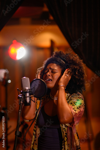 Portrait of a hispanic woman singer recording a new song in a music studio photo