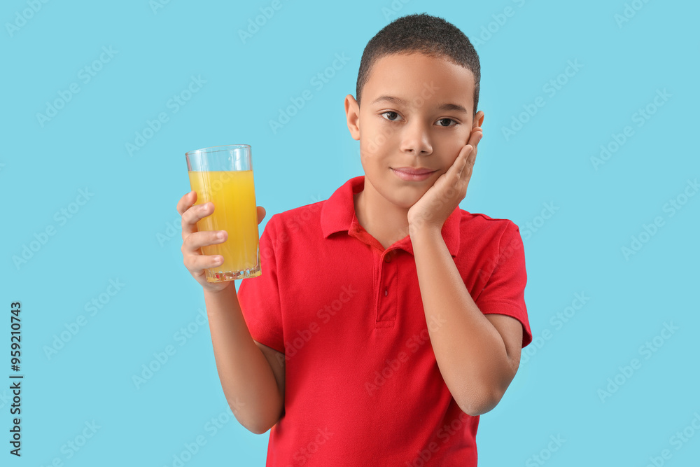Little African-American boy with glass of orange juice on blue background Little African-American boy with glass of orange juice on blue background