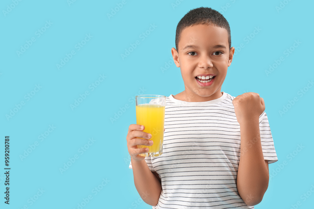 Happy little African-American boy with glass of orange juice on blue background Happy little African-American boy with glass of orange juice on blue background