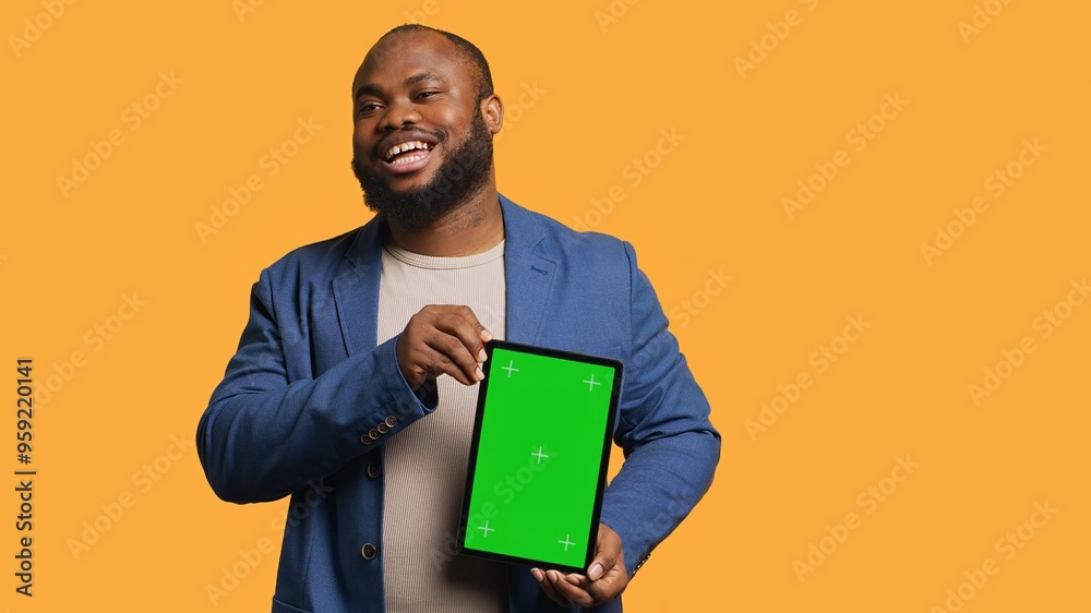 Amused african american man laughing while presenting tablet with green screen display, studio background. Joyous BIPOC person has fun during promotion for blank copy space mockup device, camera A Amused african american man laughing while presenting tablet with green screen display, studio background. Joyous BIPOC person has fun during promotion for blank copy space mockup device, camera A