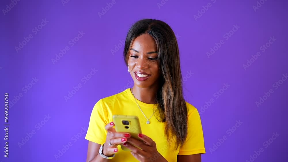 Studio portrait with purple background of a happy african urban woman using mobile phone while smiling Studio portrait with purple background of a happy african urban woman using mobile phone while smiling