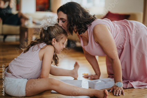 Loving mother kissing her daughter on the forehead during a tender bonding moment at home, showcasing family love and connection.