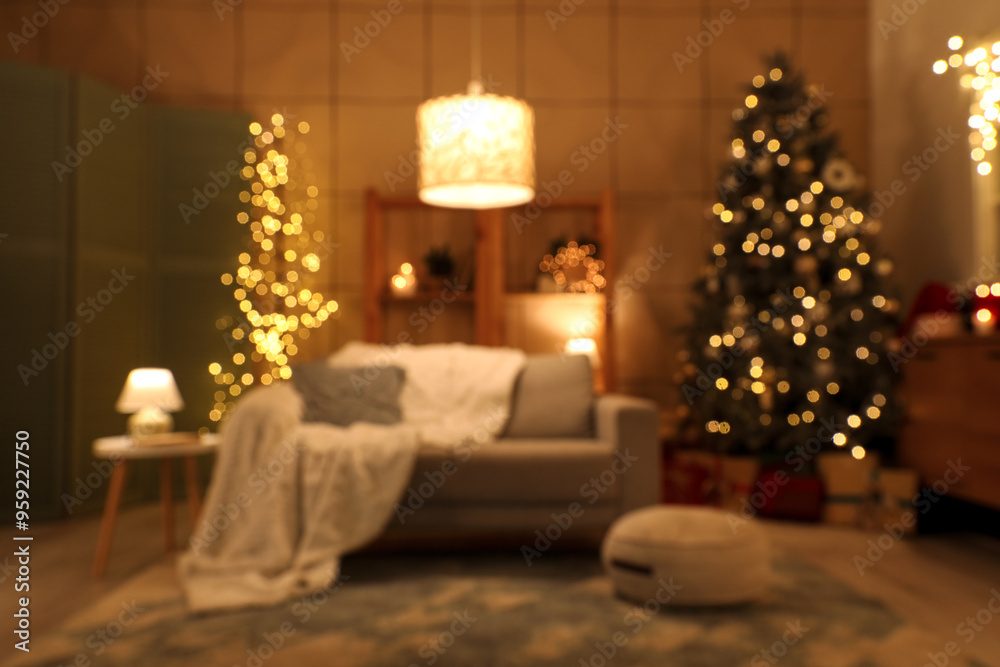 Blurred view of living room with sofa, Christmas tree and glowing lamps at night
