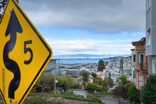 Scenic view with traffic sign allowing speed of 5 mph due to winding road at Lombard Street, San Francisco, California, USA against blue sky with clouds