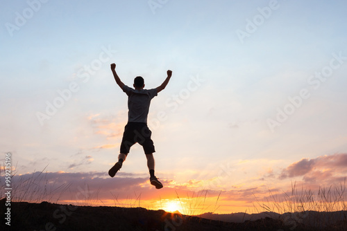 Wallpaper Mural Silhouette of a man jumping with arms raised in celebration against a stunning sunset backdrop. The image conveys the concept of celebrating life and motivation for success Torontodigital.ca
