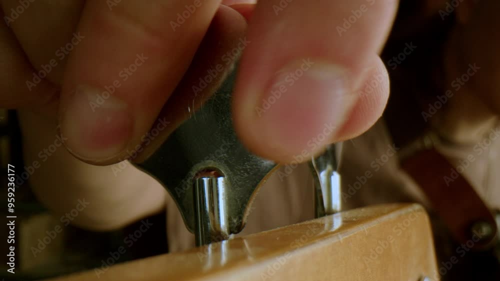 Hand of unrecognizable male musician adjusting tuning peg on guitar before playing. Close-up view Hand of unrecognizable male musician adjusting tuning peg on guitar before playing. Close-up view