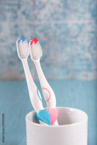 Toothbrushes in the shape of a heart in a glass on a colored background