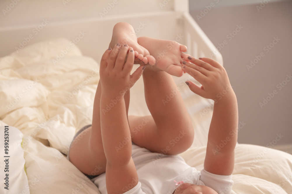 the little girl plays on the bed with her legs and hands the little girl plays on the bed with her legs and hands
