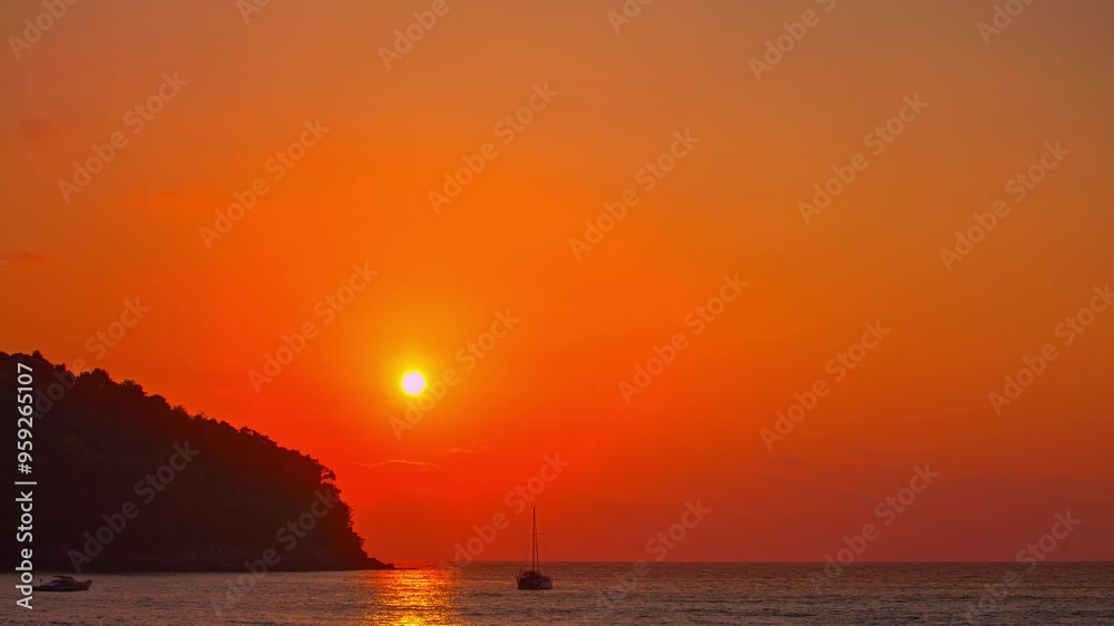 time lapse The sun is slowly falling into the sea
A tranquil scene of the sun setting over the ocean, with a silhouette of a boat and distant hills under a warm, dusky sky. Beautiful sky at sunset