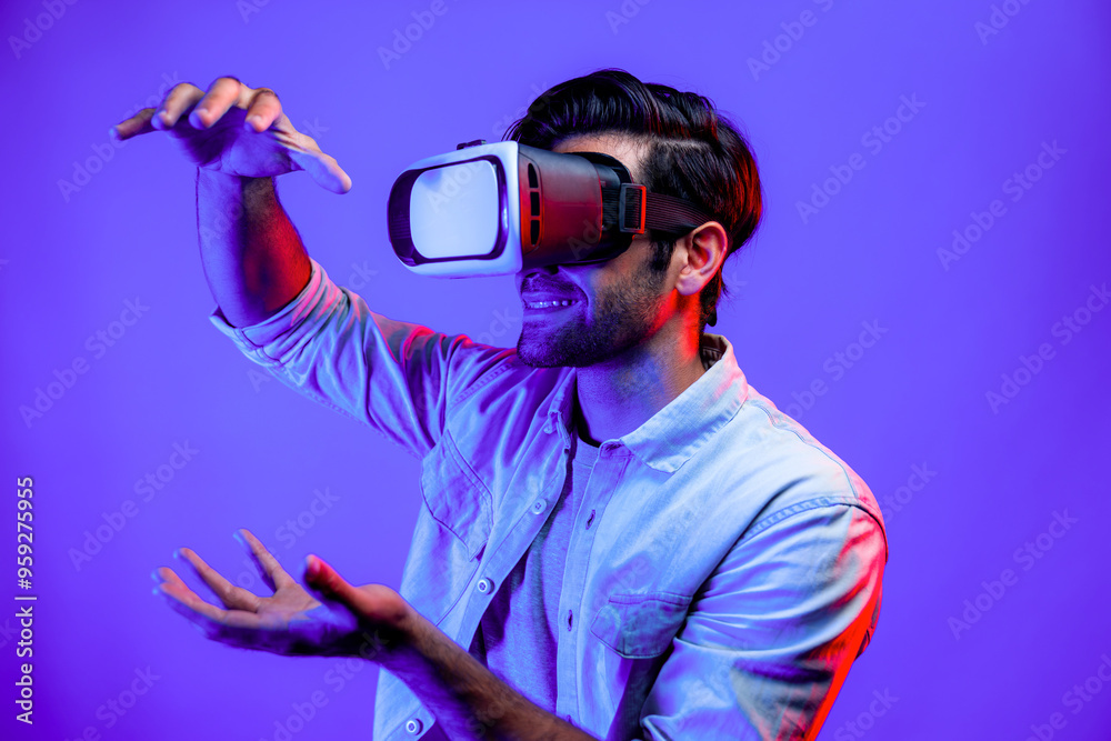 Caucasian smart man holding and moving gesture while using VR goggle. Happy person using headset and goggle while enter virtual world or metaverse with neon light background. Technology. Deviation. Caucasian smart man holding and moving gesture while using VR goggle. Happy person using headset and goggle while enter virtual world or metaverse with neon light background. Technology. Deviation.