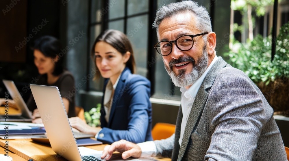 A man with a beard and glasses sitting at a table using laptops, AI