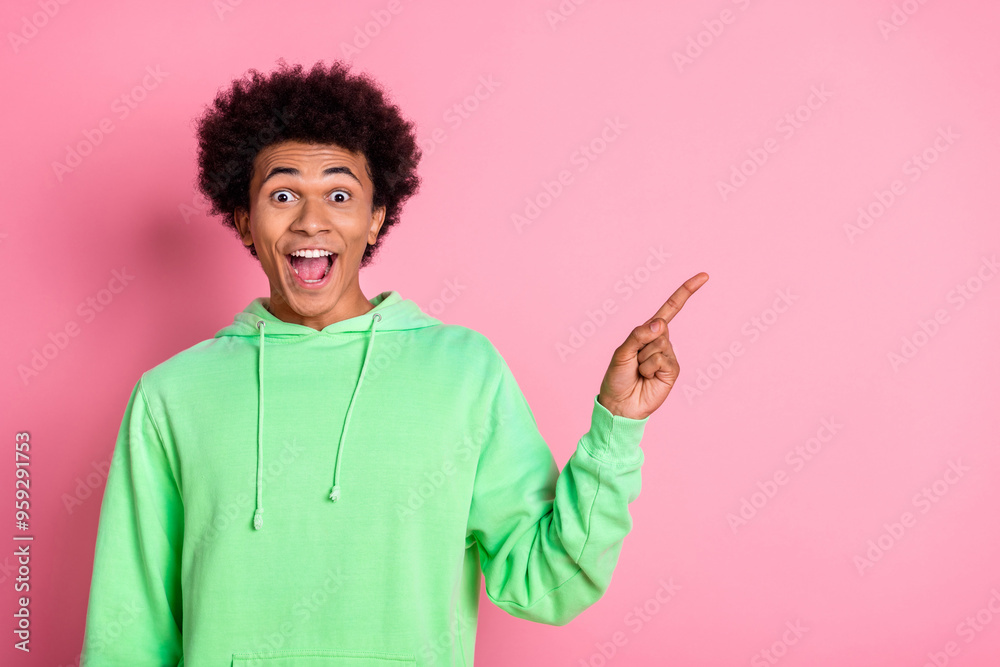 Photo of nice young man indicate finger empty space wear green hoodie isolated on pink color background Photo of nice young man indicate finger empty space wear green hoodie isolated on pink color background