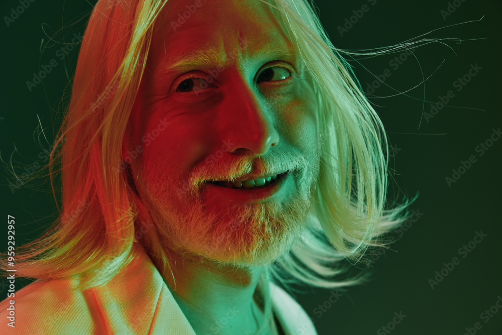 Portrait of a smiling man with long, light colored hair against a gradient green and red background, showcasing a playful and vibrant concept with soft lighting and color contrast Portrait of a smiling man with long, light colored hair against a gradient green and red background, showcasing a playful and vibrant concept with soft lighting and color contrast