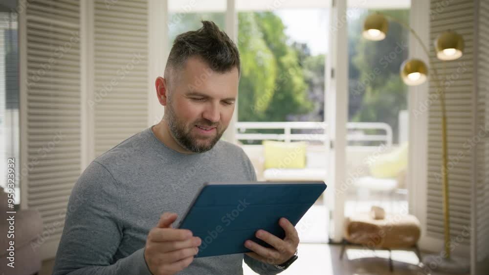 A cheerful and happy man is fully engaged with his tablet, radiating positivity and focus in a bright and stylish room, beautifully surrounded by modern decor and abundant natural light A cheerful and happy man is fully engaged with his tablet, radiating positivity and focus in a bright and stylish room, beautifully surrounded by modern decor and abundant natural light