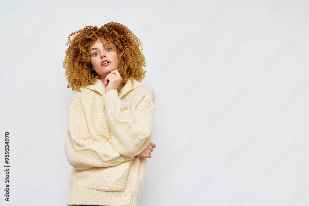 Young woman with curly hair in a cozy sweater, posing against a neutral white background, expressing a thoughtful and stylish demeanor with a relaxed ambiance Young woman with curly hair in a cozy sweater, posing against a neutral white background, expressing a thoughtful and stylish demeanor with a relaxed ambiance