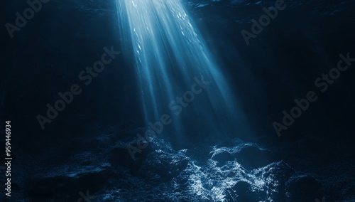 A beam of sunlight shines through the dark blue water, illuminating the ocean floor.