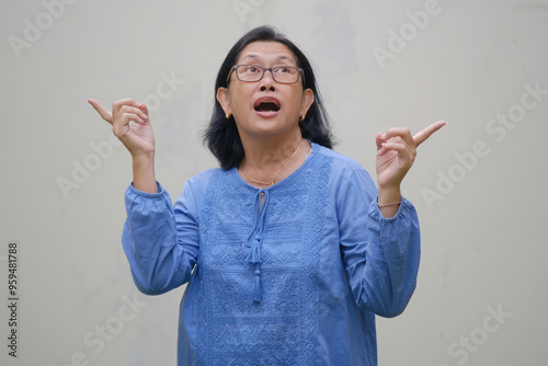 A woman is looking up; her fingers pointing to her left and right; happy, surprised expression photo