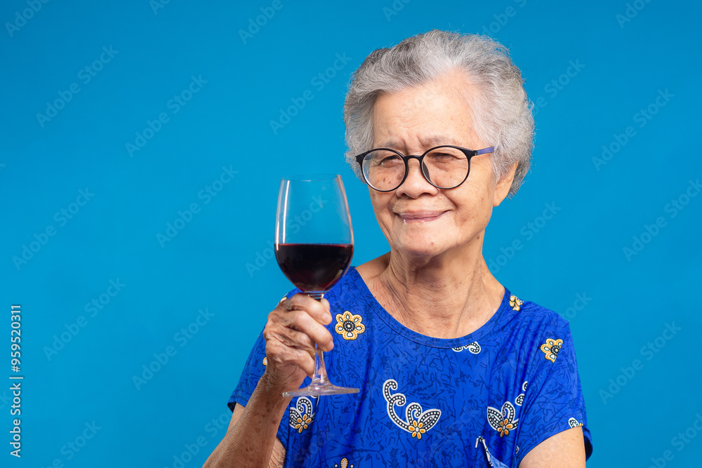 Senior woman enjoying red wine in blue dress, symbol of relaxation and joy Senior woman enjoying red wine in blue dress, symbol of relaxation and joy