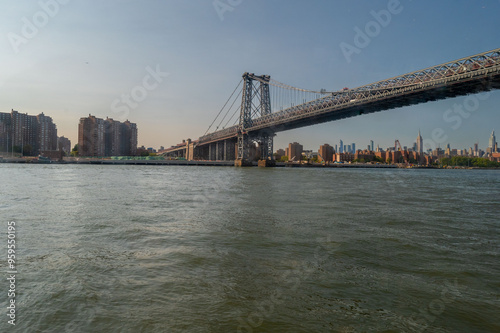 Taken from a ferry on the way to New York City, this picturesque view captures the calm waters, with the city's towering skyline illuminated by the city's lights. The Manhattan Bridge stands prominent
