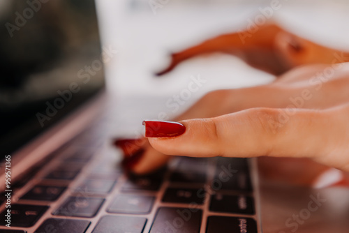 Hands Typing Laptop Keyboard Close Up - Woman's hands with red nail polish typing on a laptop keyboard. photo