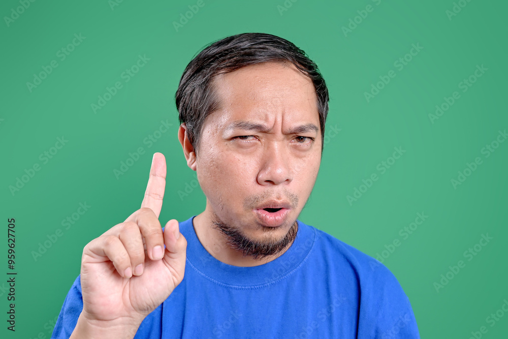 Young Asian Man Showing No Sign With Index Finger Over Green Background