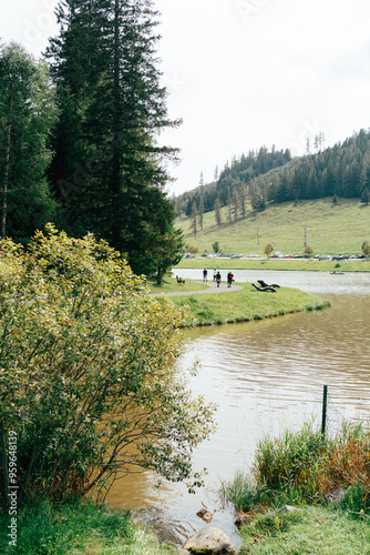 People walking along a riverbank on a sunny day in a scenic rura photo