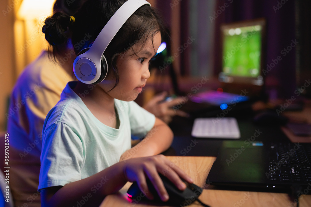 Asian young girl is playing a video game with a computer mouse. She is wearing headphones and she is focused on the game Asian young girl is playing a video game with a computer mouse. She is wearing headphones and she is focused on the game