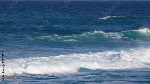 Slow motion footage of pure blue ocean water, with waves crashing powerfully and light reflecting off the surface, capturing the raw energy of a storm at sea
