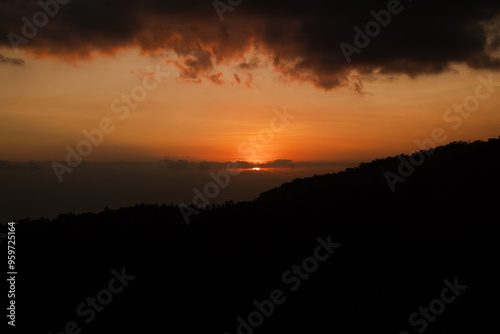 Sunset behind clouds and silhouetted hills