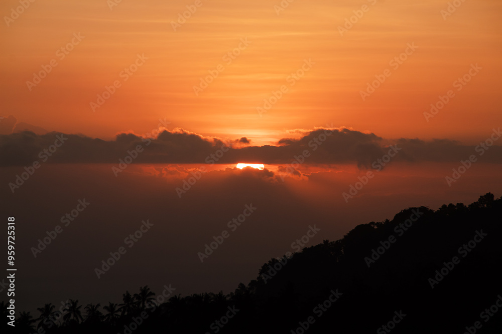 Sunset behind clouds and silhouetted hills