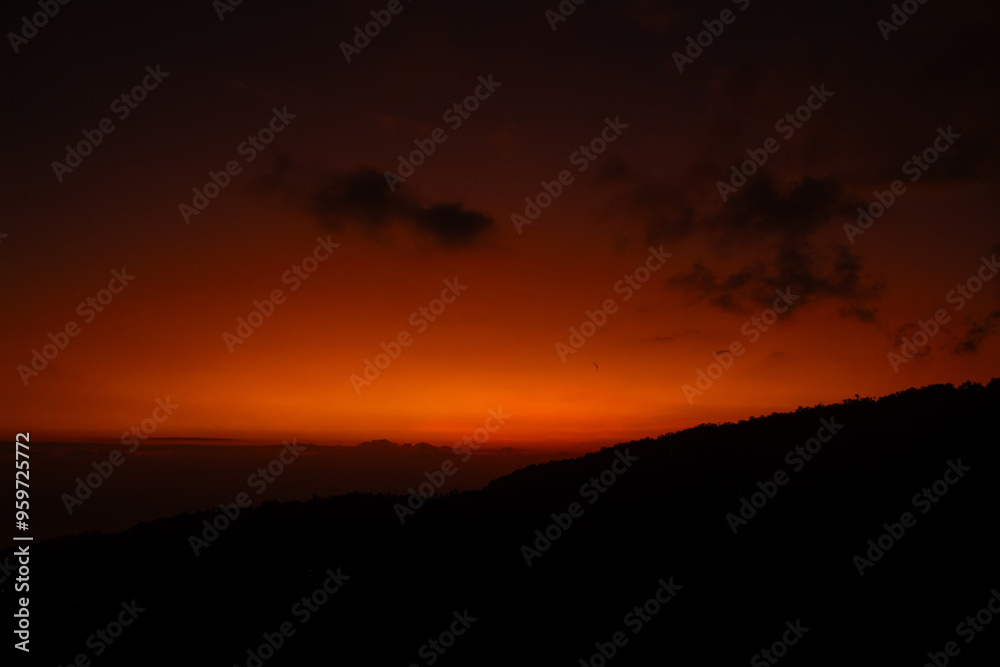 Sunset behind clouds and silhouetted hills