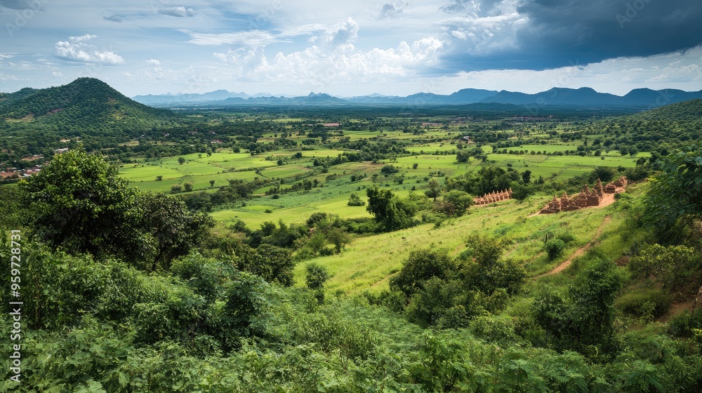 Fototapeta premium Top view of Oudongas countryside, with green fields and ancient stupas visible in the distance.