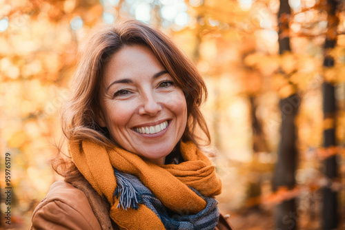 Portrait in the forest of a pleased 50 years old woman. Joyful woman in an outdoor fall scenery having fun at the autumn season. 