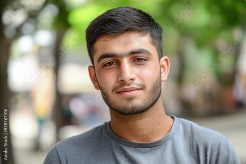 A close-up portrait of a young Indian or Pakistani man wearing a casual t-shirt, with a blurred background.