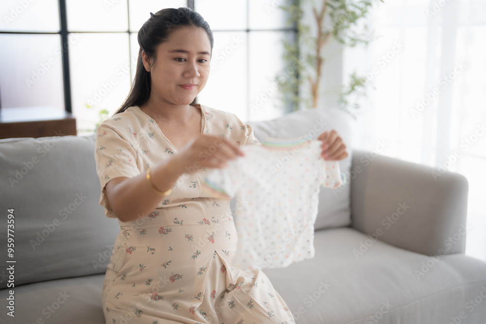 Pregnant asian woman getting ready for the maternity hospital preparing and planning baby clothes for new baby of pregnancy packing baby stuff on bed. Pregnant asian woman getting ready for the maternity hospital preparing and planning baby clothes for new baby of pregnancy packing baby stuff on bed.
