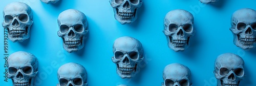 Several white skulls presented in a grid formation against a blue background, creating a high contrast and thought-provoking visual effect that highlights human fragility.