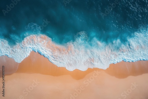 Top view of a vast ocean meeting a sandy beach. Vibrant blue with waves crashing onto the shore.