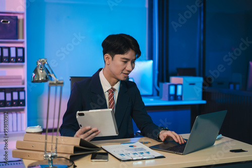 Businessman using digital tablet analyzes business data, busy working on laptop computer with smart phone and business report on office desk, business strategy analysis concept.