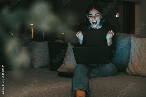 Happy woman celebrating in front of her laptop, exulting with joy after achieving a significant milestone, such as winning a sports bet, acing an exam, or finding a new job or online date, embracing