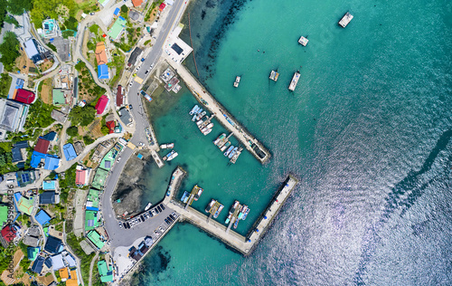 Silan, Sacheon-si, Gyeongsangnam-do, South Korea - May 22, 2021: Aerial and top angle view of Sanbunryeong Port with fishing village and fishing boats moored inside a breakwater photo