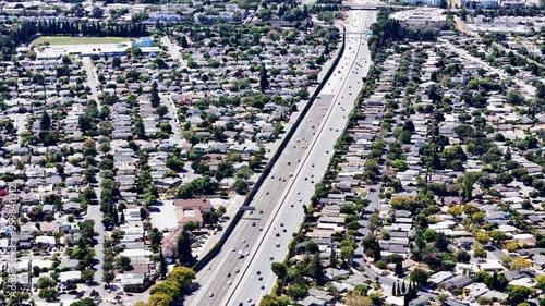 Aerial view of a busy highway running through a residential neighborhood in Silicon Valley, California. Perfect for showcasing suburban infrastructure, traffic, and urban planning in stock footage.