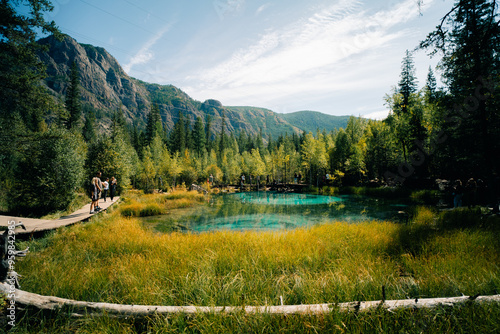 Blue geyser lake in autumn forest after snowfall. Altai, Siberia, Russia. Beautiful autumn landscape