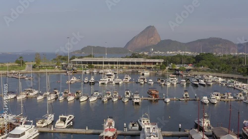 Sunlit aerial approach of Sugarloaf mountain in Rio de Janeiro over sailing boats in the gloria Marina / Marina da Gloria